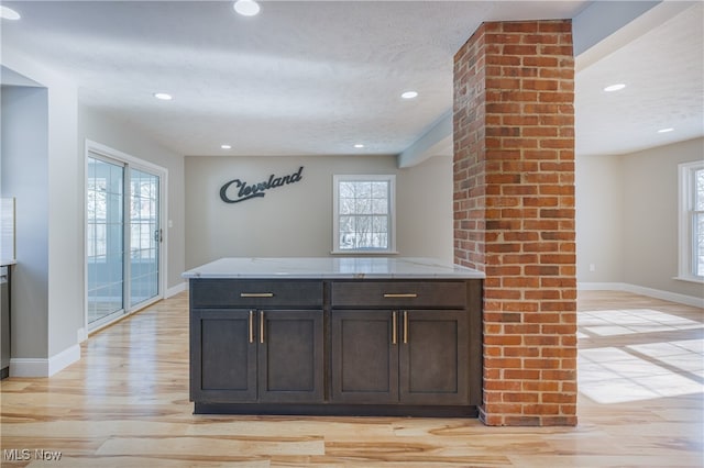 kitchen featuring light stone countertops, light hardwood / wood-style flooring, dark brown cabinets, and a healthy amount of sunlight