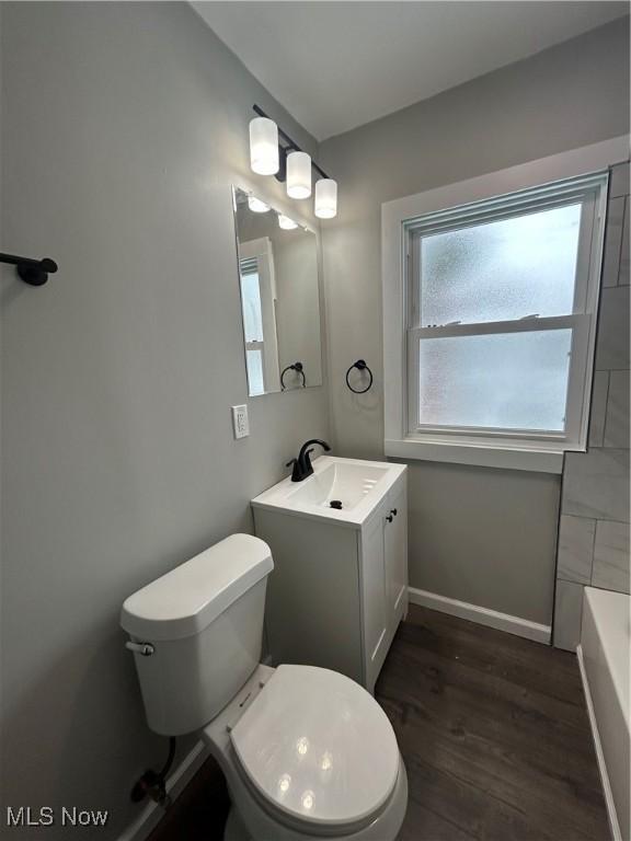 bathroom with wood-type flooring, a tub, toilet, and vanity