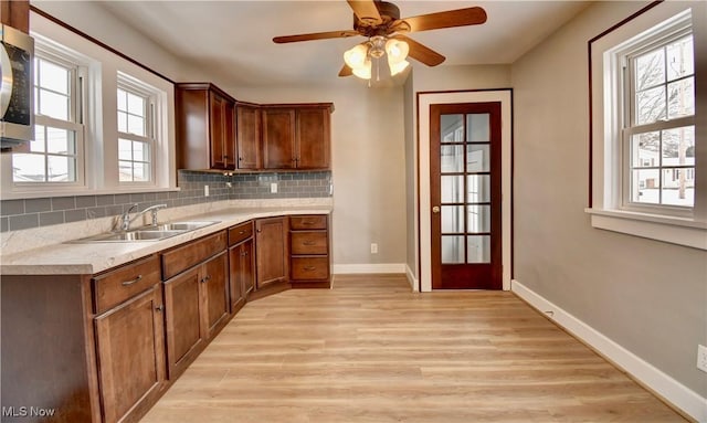 kitchen with light hardwood / wood-style floors, sink, ceiling fan, and tasteful backsplash