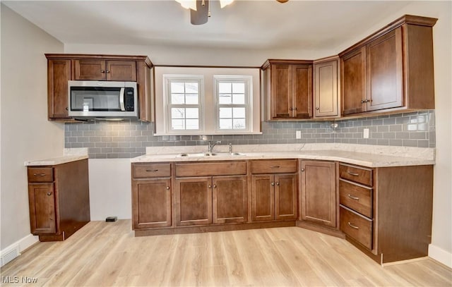 kitchen with sink, backsplash, light hardwood / wood-style flooring, and light stone countertops