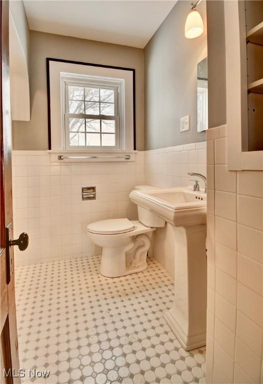 bathroom with tile walls, toilet, and tile patterned flooring