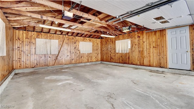 garage featuring a garage door opener and wooden walls