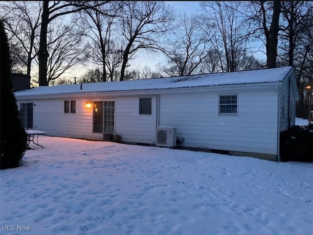 snow covered rear of property with ac unit