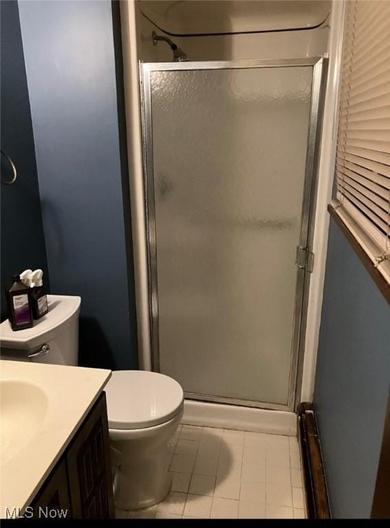 bathroom featuring toilet, tile patterned flooring, walk in shower, and vanity