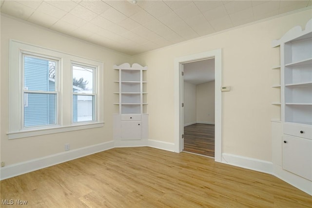 unfurnished room featuring ornamental molding and light hardwood / wood-style flooring