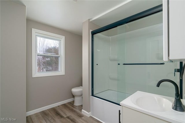 full bathroom featuring vanity, hardwood / wood-style flooring, enclosed tub / shower combo, and toilet