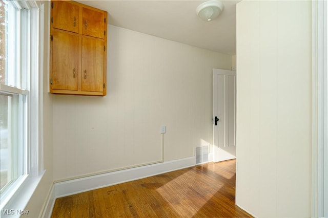 empty room with plenty of natural light and hardwood / wood-style floors