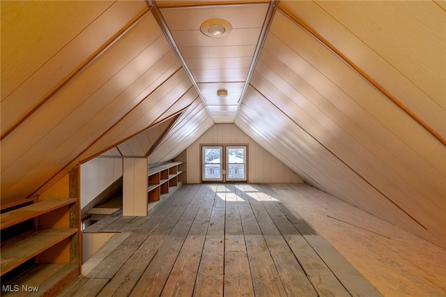 bonus room with lofted ceiling, hardwood / wood-style flooring, and wooden walls