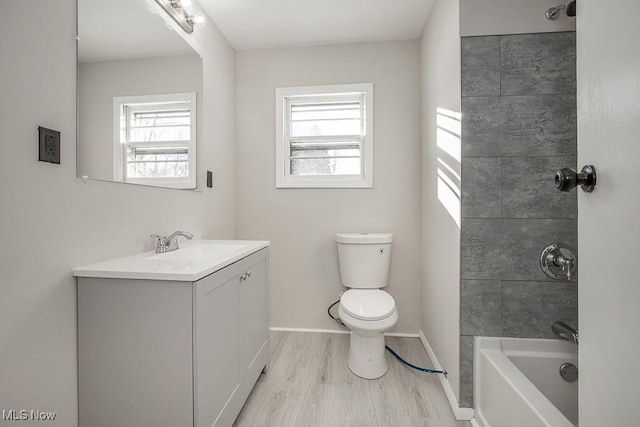 full bathroom with wood-type flooring, toilet, vanity, and a healthy amount of sunlight