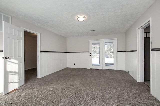 carpeted empty room featuring french doors and a textured ceiling