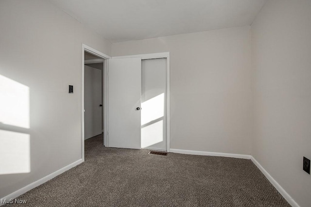 unfurnished bedroom featuring a closet and dark carpet