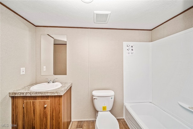 full bathroom with hardwood / wood-style floors, vanity, ornamental molding, toilet, and a textured ceiling