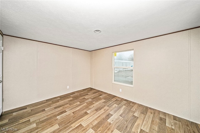 spare room featuring hardwood / wood-style flooring, ornamental molding, and a textured ceiling