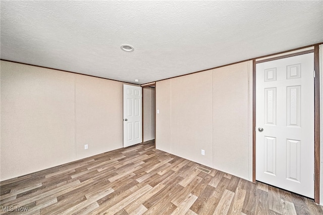 basement featuring light hardwood / wood-style flooring and a textured ceiling