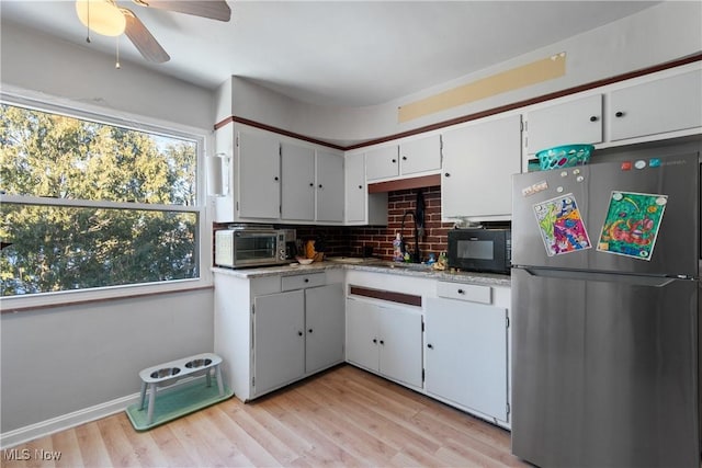 kitchen with decorative backsplash, plenty of natural light, white cabinets, and stainless steel fridge