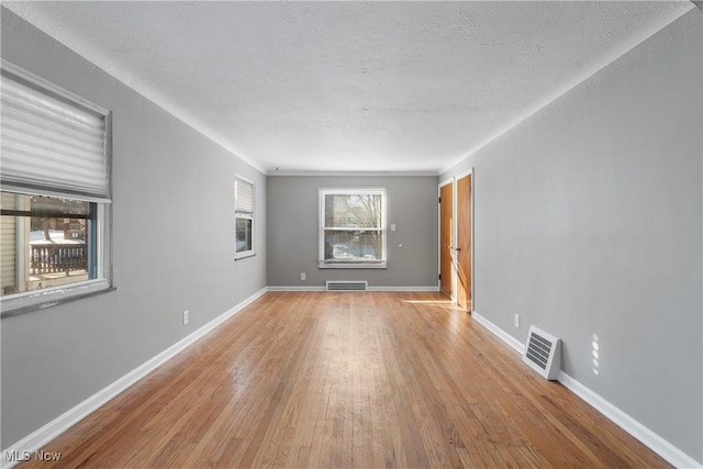 spare room with light hardwood / wood-style floors and a textured ceiling