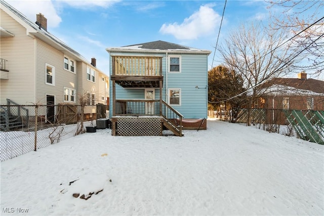 snow covered rear of property with cooling unit, a balcony, and a deck