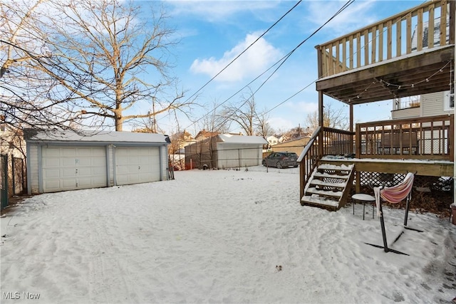 yard covered in snow with a garage, a wooden deck, and an outdoor structure