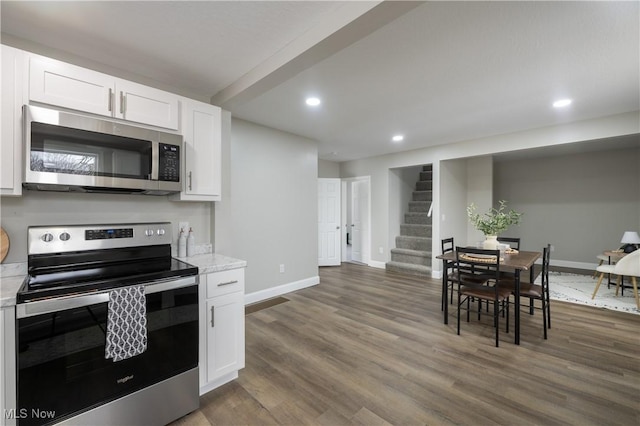 kitchen featuring light stone countertops, white cabinets, appliances with stainless steel finishes, and dark hardwood / wood-style flooring