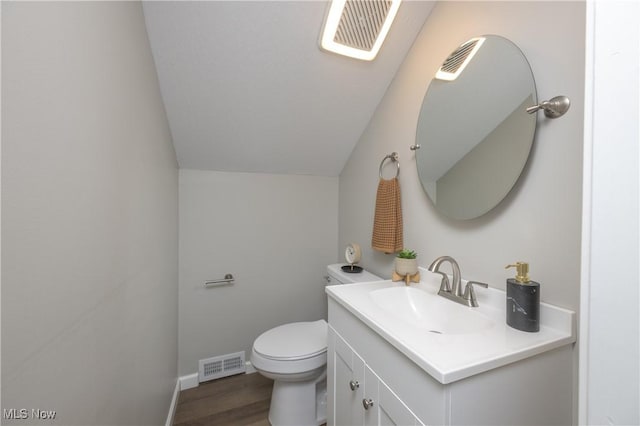 bathroom with hardwood / wood-style floors, toilet, vanity, and lofted ceiling