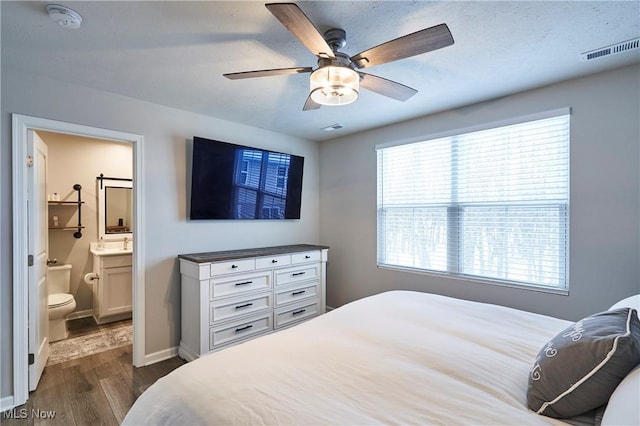 bedroom featuring ceiling fan, connected bathroom, and dark hardwood / wood-style flooring