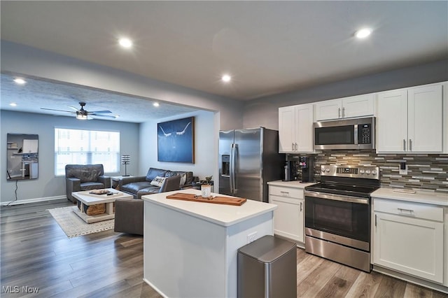 kitchen with white cabinets, a kitchen island, appliances with stainless steel finishes, and tasteful backsplash