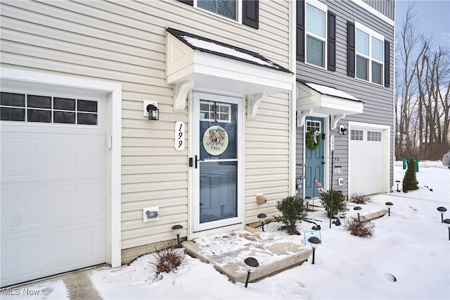 snow covered property entrance featuring a garage