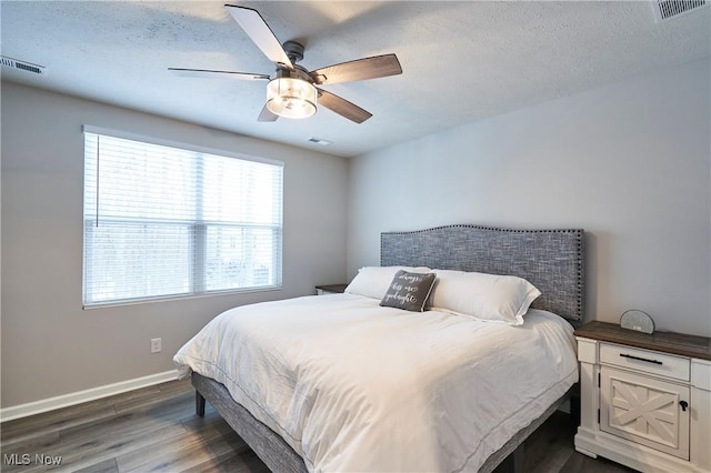 bedroom with ceiling fan, dark wood-type flooring, and a textured ceiling