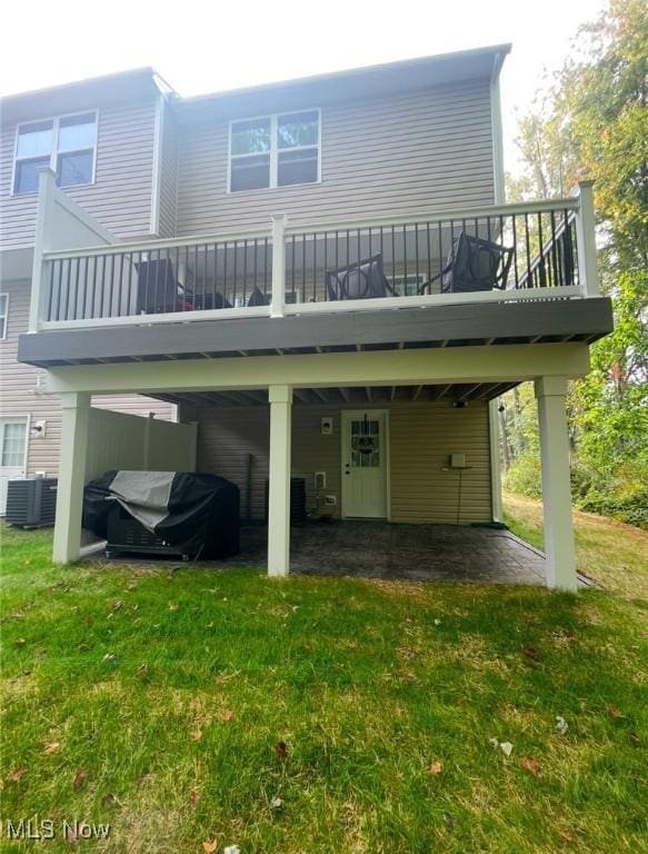 rear view of property featuring a lawn, cooling unit, and a deck