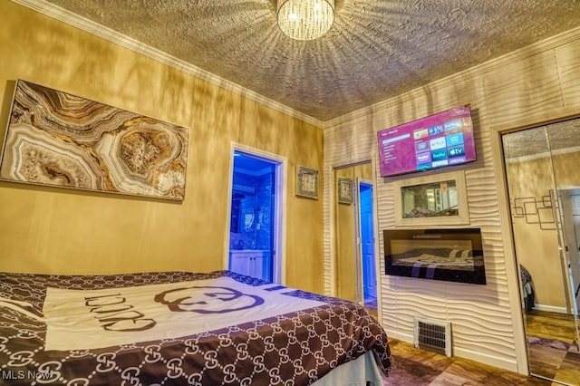 bedroom with crown molding, a textured ceiling, ensuite bath, and a notable chandelier