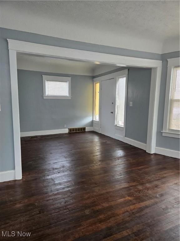 interior space with a textured ceiling, dark hardwood / wood-style flooring, and a healthy amount of sunlight