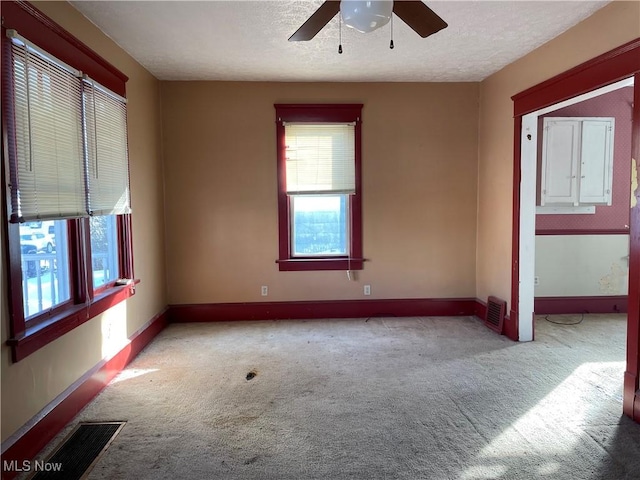 spare room featuring ceiling fan, a textured ceiling, and light carpet