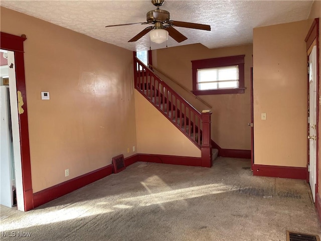 unfurnished living room with ceiling fan, a textured ceiling, and carpet