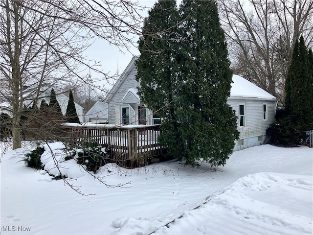 snow covered back of property featuring a wooden deck