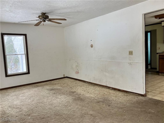 empty room with ceiling fan and a textured ceiling