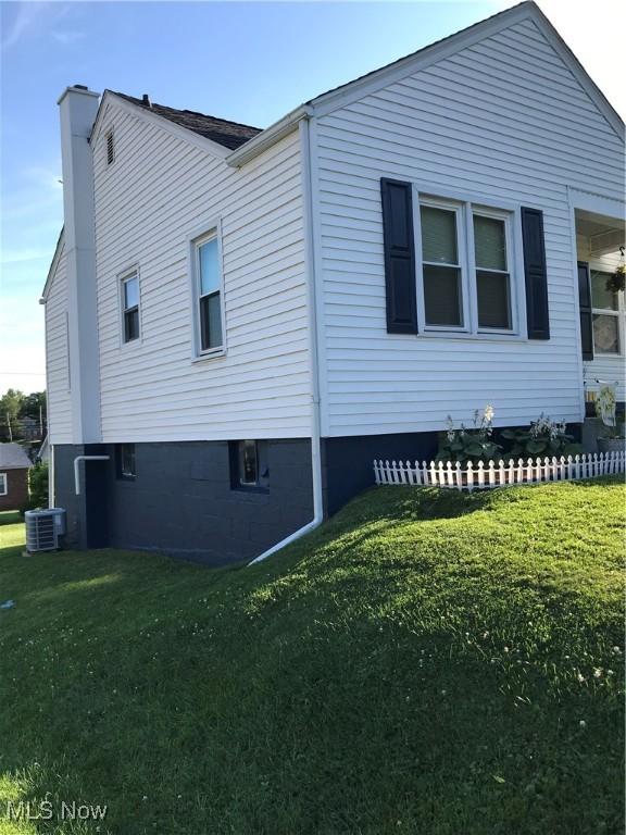 view of side of home featuring a lawn and central AC