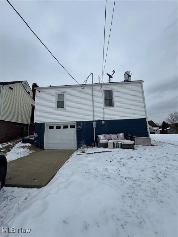 snow covered rear of property with a garage