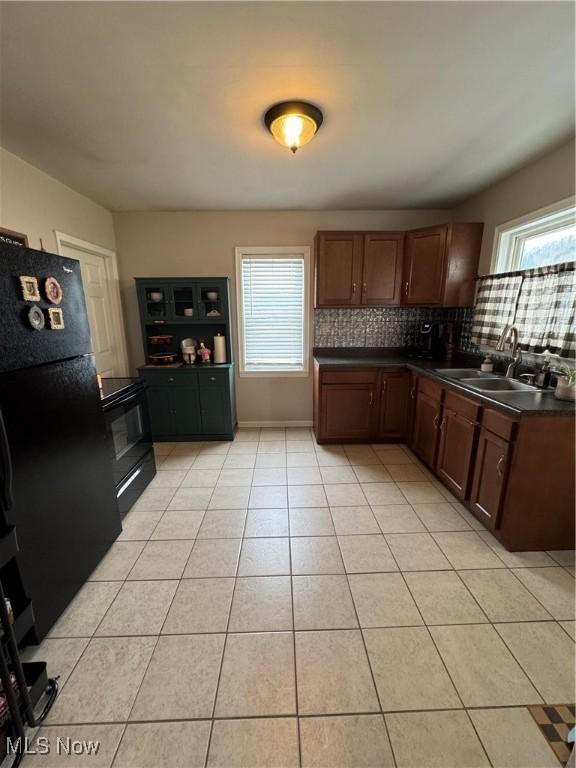 kitchen featuring sink, a wealth of natural light, light tile patterned floors, and black appliances