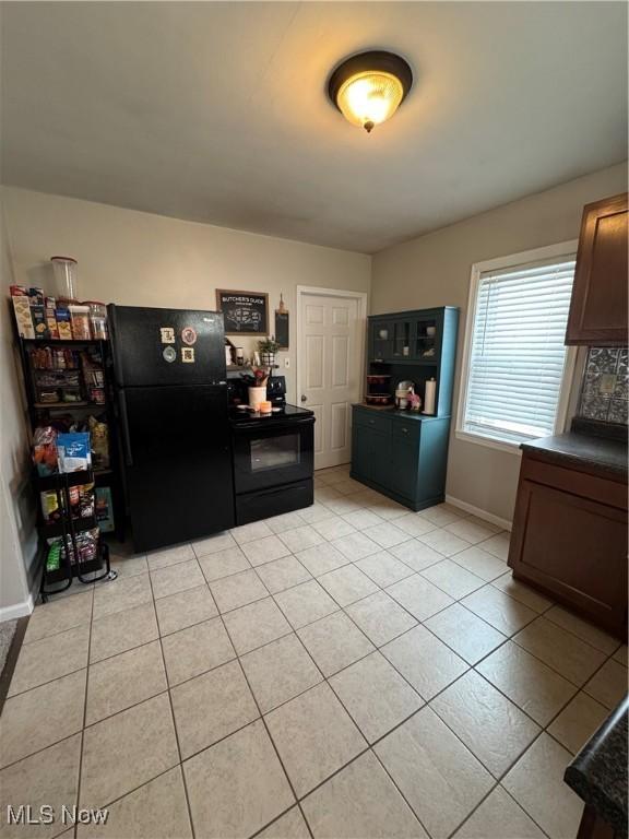 interior space featuring black appliances and light tile patterned flooring