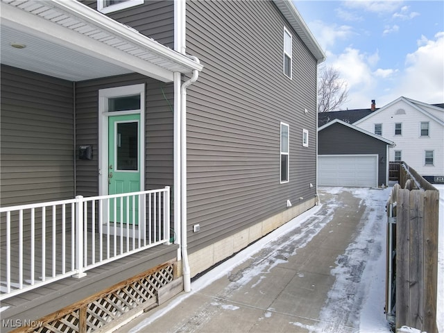 snow covered property with a garage and an outdoor structure