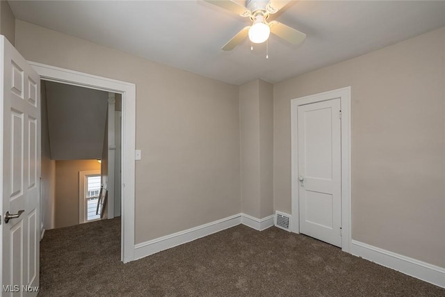 unfurnished room featuring a ceiling fan, visible vents, baseboards, and dark colored carpet