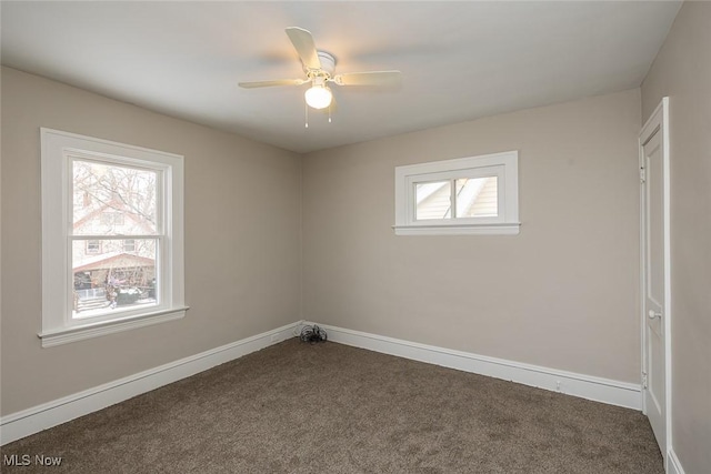 spare room with baseboards, ceiling fan, and dark carpet