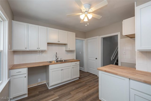 kitchen featuring dark wood finished floors, butcher block counters, decorative backsplash, a ceiling fan, and a sink