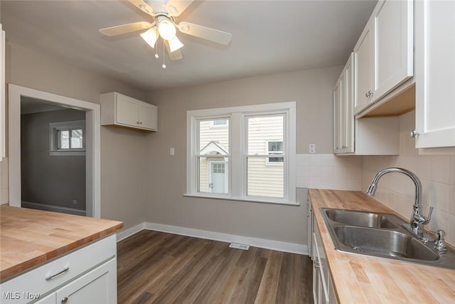 kitchen with a sink, tasteful backsplash, white cabinetry, and butcher block counters