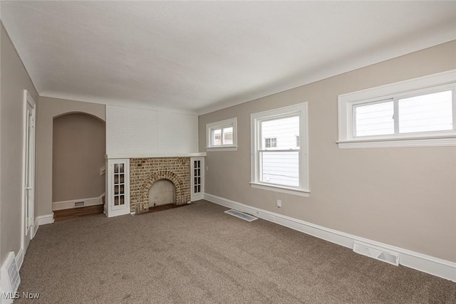 unfurnished living room featuring visible vents, plenty of natural light, and a brick fireplace