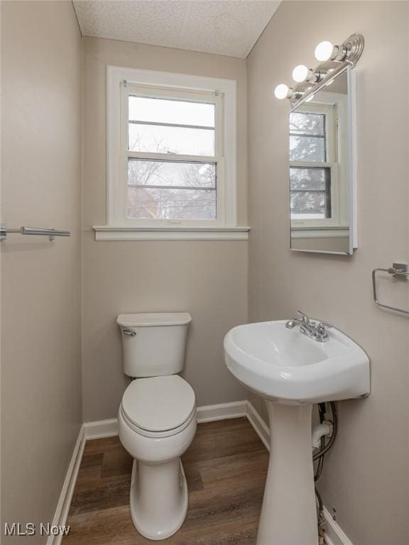 bathroom with toilet, baseboards, and wood finished floors