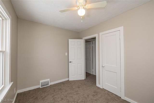 unfurnished bedroom featuring ceiling fan, carpet, visible vents, and baseboards