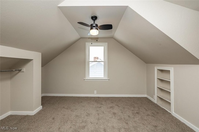 additional living space with baseboards, carpet floors, built in shelves, and vaulted ceiling