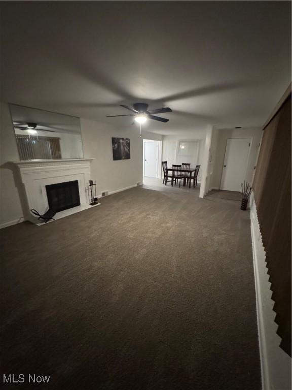 unfurnished living room featuring ceiling fan and carpet flooring