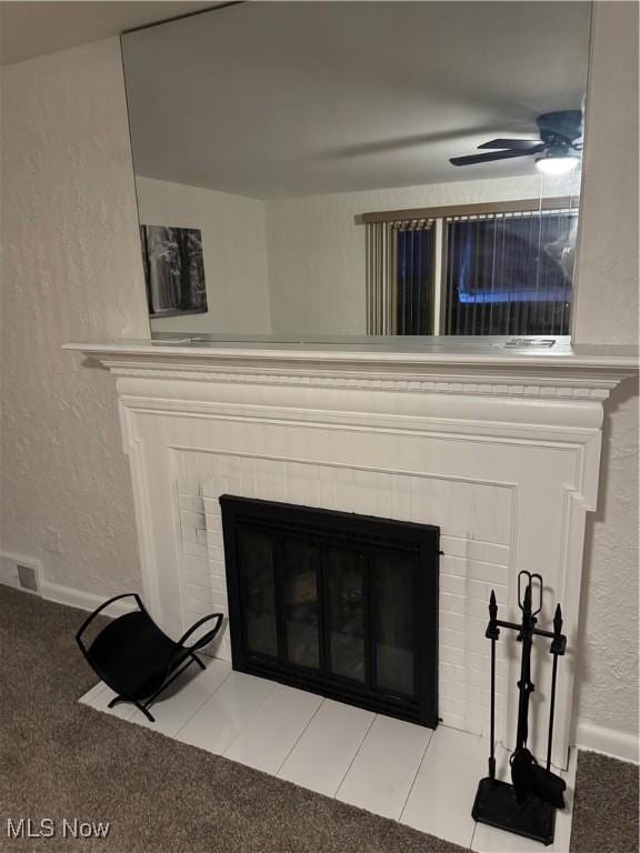 details featuring a tiled fireplace, ceiling fan, and carpet flooring